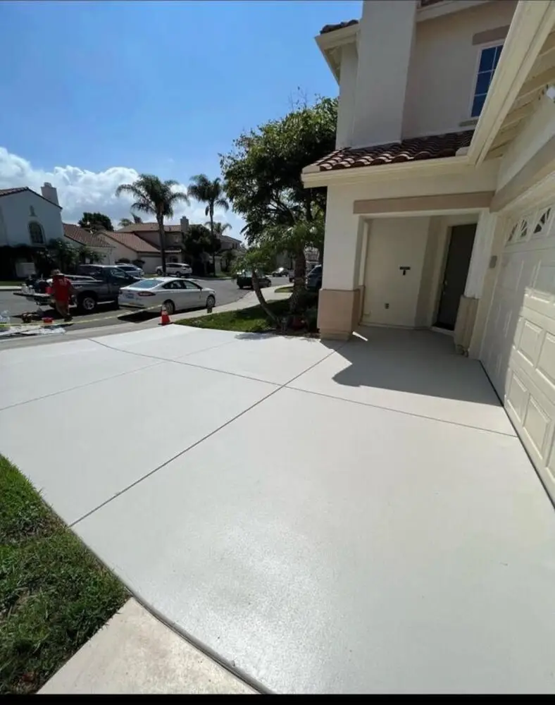 Freshly coated light gray concrete driveway with level slab joints in front of a San Diego home, finished by Turbo Surfacing Solutions